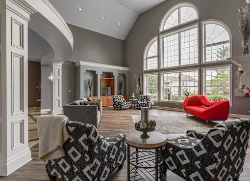 A living room with a red chair and a black and white patterned couch at Twin Fountains Apartments, Mason