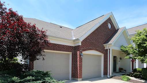 A house with a red brick facade and a white garage door at Twin Fountains Apartments, Mason, OH