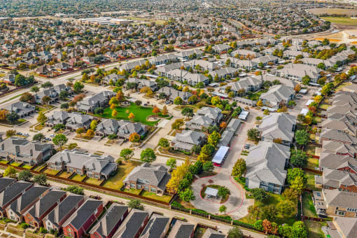 City aerial view with green lawn at Riachi at One21, Texas