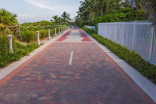 A red brick pathway leads through a tropical setting.