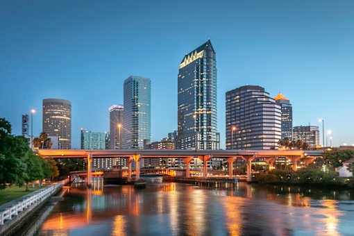 A cityscape at dusk with a bridge crossing a river.
