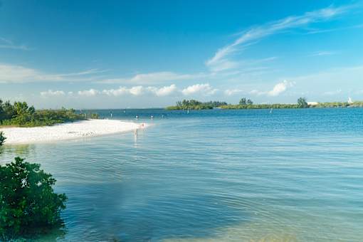 A serene beach landscape with a clear blue sky and calm waters.