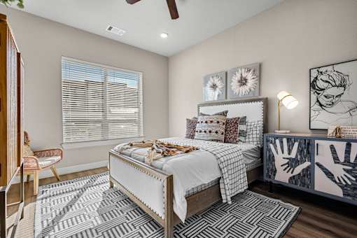 A bedroom with a bed, a chair, and a ceiling fan.