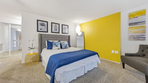 a bedroom with a yellow accent wall and a bed