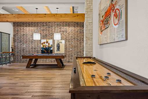 A billiard table is in the middle of a room with a brick wall and a bench.