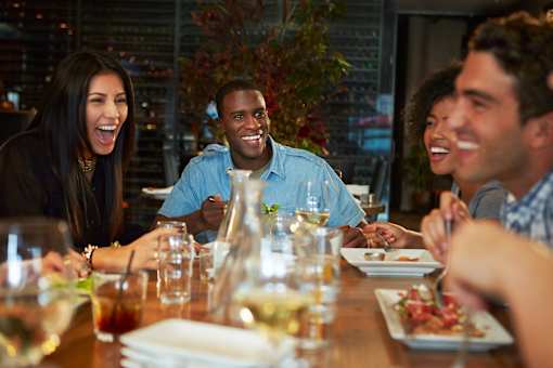 A group of people are sitting around a table eating and drinking.