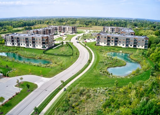 an aerial view of multiple apartment buildings with lakes and a road