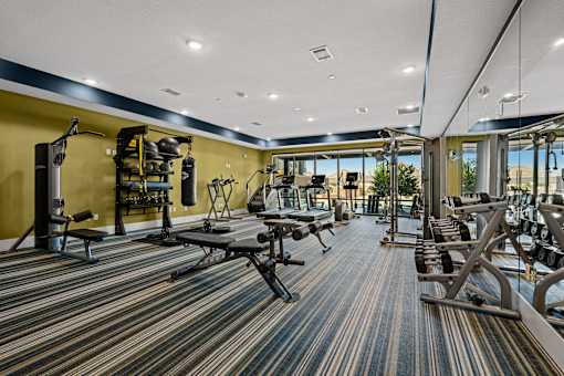 A gym with a variety of equipment including weights and benches.
