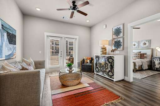A living room with a brown couch and a red rug.