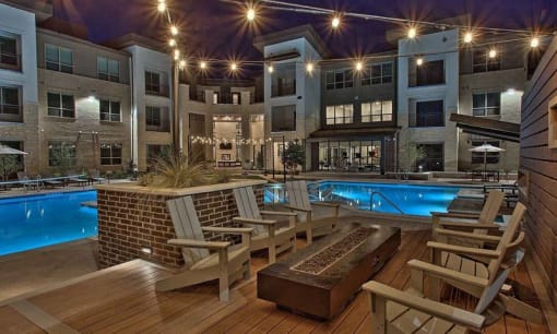 a swimming pool with rocking chairs in front of an apartment building at Hunters Creek Apartments, Denton Texas