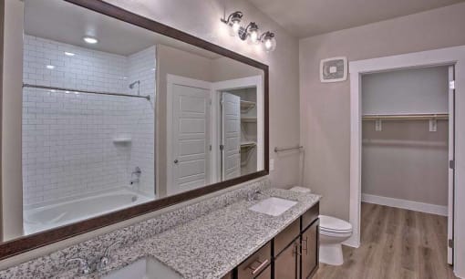 a bathroom with a sink and a large mirror at Hunters Creek Apartments, Denton, TX