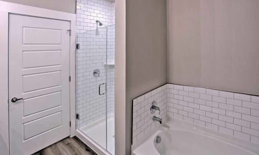 a bathroom with a tub and a shower and a door at Hunters Creek Apartments, Denton, 76210