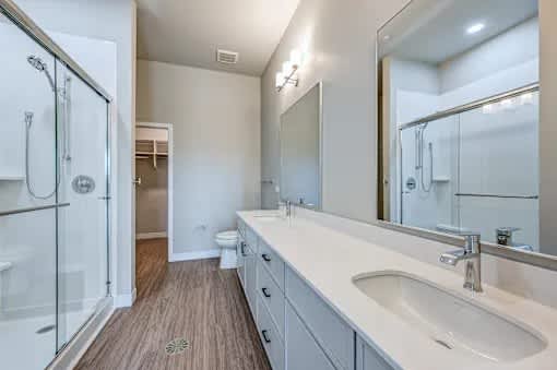 A bathroom with a sink, mirror, and shower.