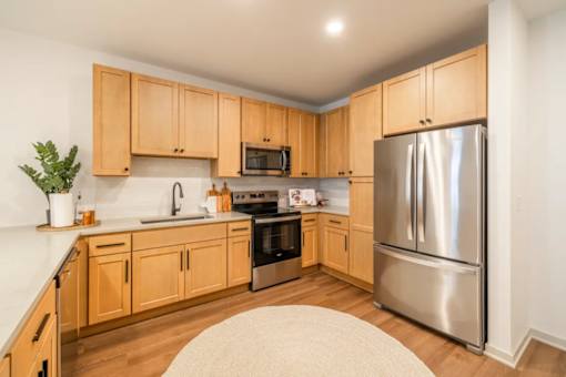 A kitchen with wooden cabinets and a stainless steel refrigerator.