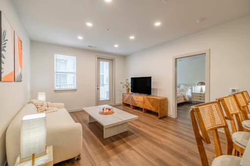 A living room with a white sofa, wooden coffee table, and a television.