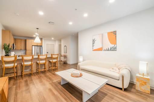 A living room with a white couch, wooden chairs, and a painting on the wall.