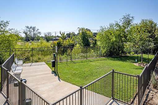 A backyard with a deck and a metal fence.