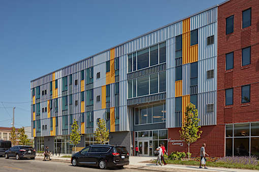 A modern building with a glass facade and a red brick building next to it.