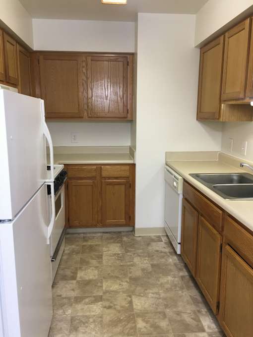 A kitchen with a white counter top and wooden cabinets.