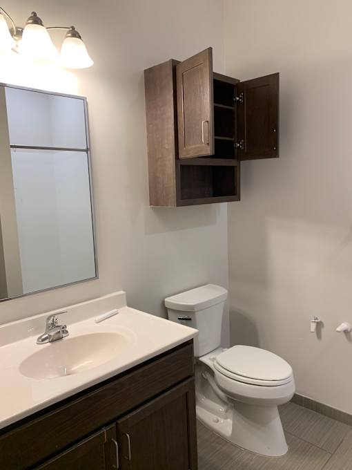 A white bathroom with a toilet, sink, and wooden floors.