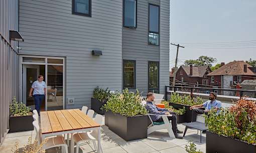 Two men are sitting on chairs and talking in a patio area.