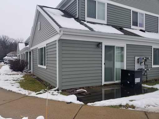A house with a grey siding and a black mailbox.