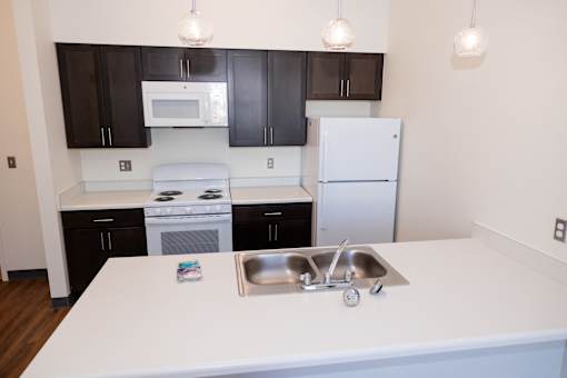 A kitchen with a white counter top and a white sink.