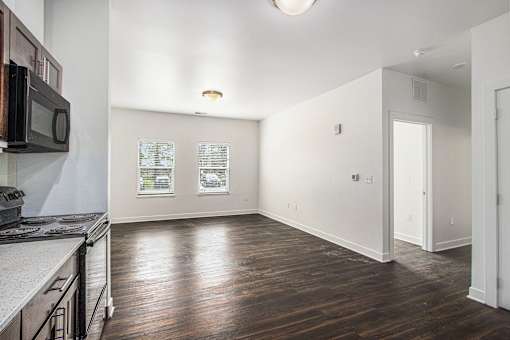 A kitchen with a microwave on the wall and a wooden floor.