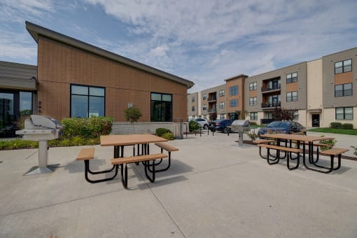 an outside patio area with picnic tables in front of an apartment building