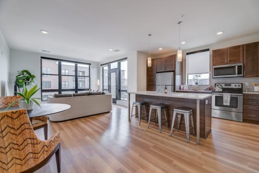 an open kitchen and living room with a large island with bar stools at Statesman Apartments, Franklin, Wisconsin