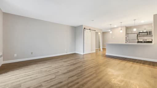 an empty living room and kitchen with wood flooring