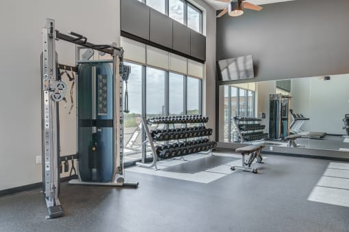 a fitness room with weights and cardio equipment and large windows
