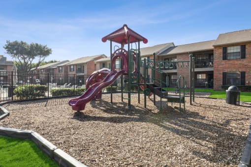 our apartments have a playground with a slide and picnic table at Wellington at Willow Bend Apartments, Plano, TX