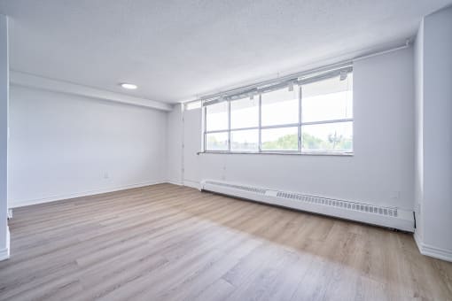 an empty living room with wood floors and a large window