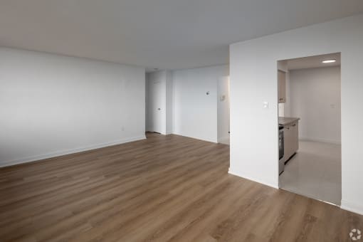 a living room and kitchen with white walls and wood flooring