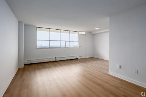an empty living room with wood floors and a window