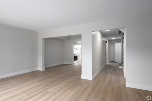an empty living room and hallway with wood floors and white walls