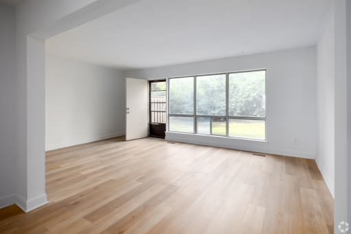 an empty living room with wood floors and a large window
