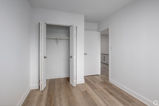 an empty room with white walls and a door to a closet