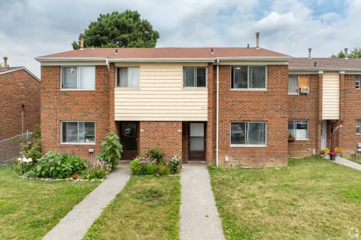 a brick house with a sidewalk in front of it