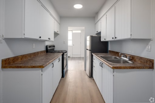 an empty kitchen with white cabinets and counters and a refrigerator