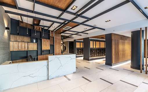 A modern office lobby with a white marble reception desk and wooden accents.