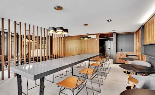 A long table with chairs is surrounded by wooden slats on the wall.