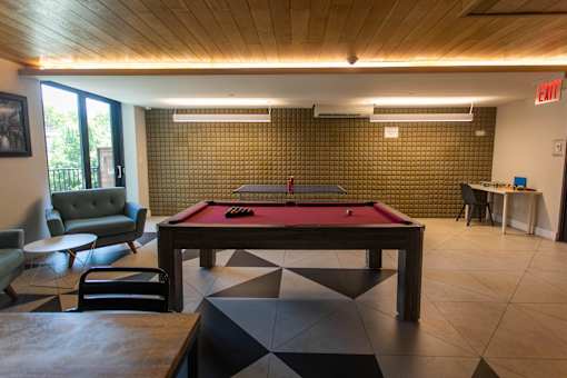 A room with a pool table and a green couch.