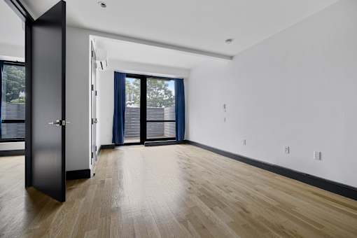 A room with a black door and wooden flooring.
