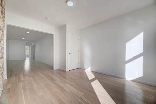 an empty living room and hallway with white walls and wood floors