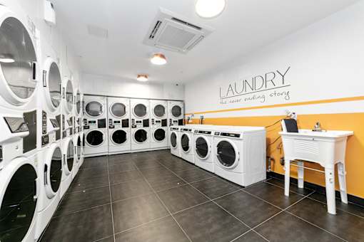a washer and dryer room with a bunch of washing machines and a table