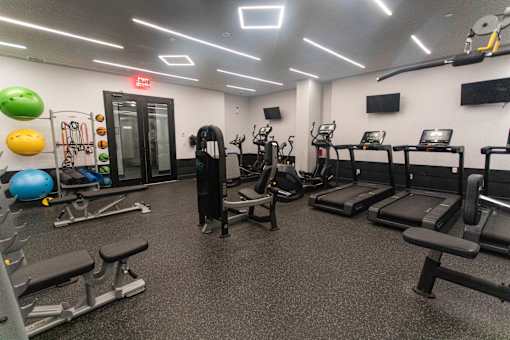 A gym with treadmills, weights, and exercise balls.