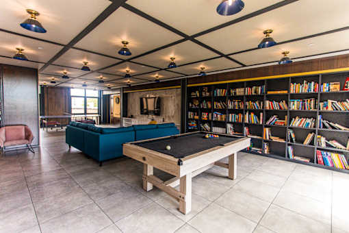 A room with a pool table and a bookshelf.