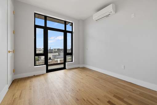 an empty living room with a large window and wooden floors